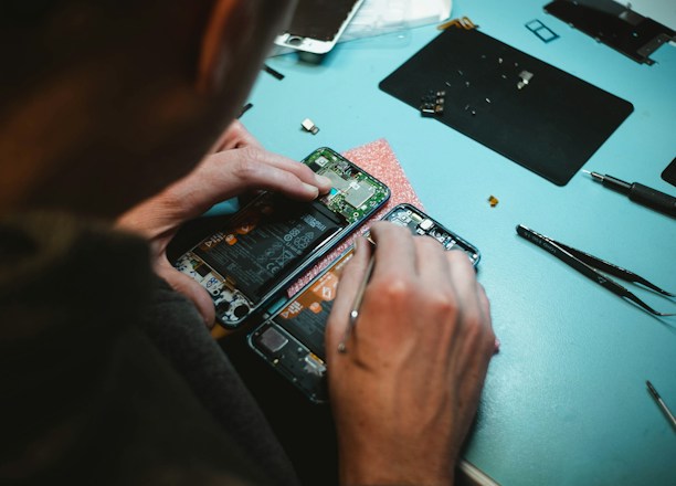 person repairing smartphones under a lighted table